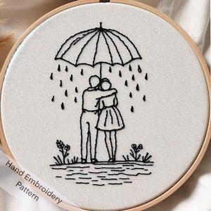 May include: Black and white embroidery pattern of a couple standing under an umbrella in the rain. The embroidery is on a white fabric background.
