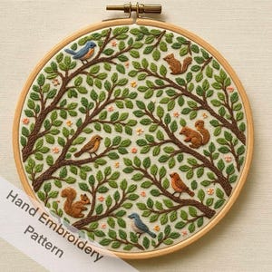 May include: A hand-embroidered pattern in a wooden hoop. The design features a tree with green leaves, brown branches, and several birds and squirrels. The text "Hand Embroidery Pattern" is visible.