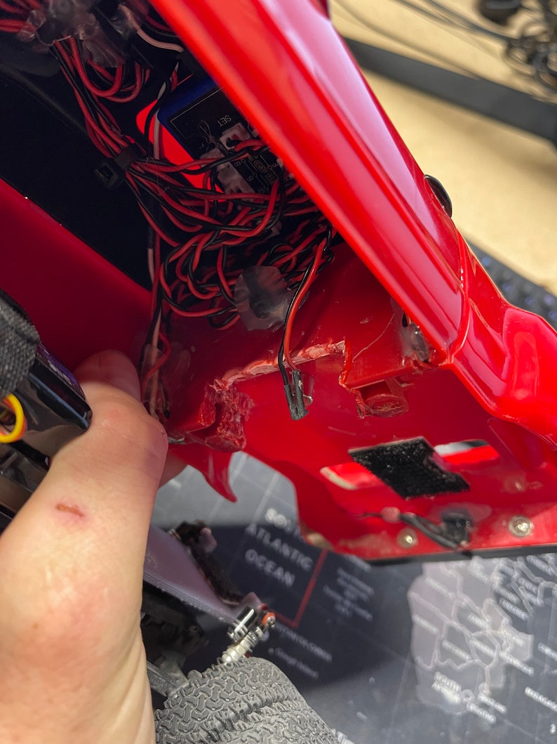Op de afbeelding: Een rode kunststof carrosserie met een zwart-wit printplaat en draden erin. De carrosserie is open en de draden zijn zichtbaar. De printplaat heeft het nummer 135 erop.
