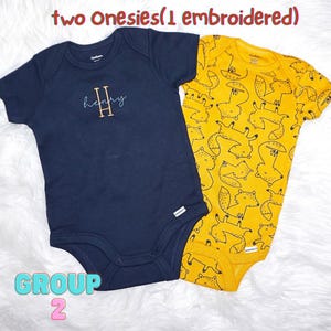 Puede incluir: Dos bodys de beb&eacute; de manga corta. Uno es azul marino liso con el nombre Henry bordado y una letra H grande. El otro es amarillo con un patr&oacute;n repetitivo de zorros en l&iacute;neas negras. El texto dice: two Onesies(1 embroidered) GROUP 2.