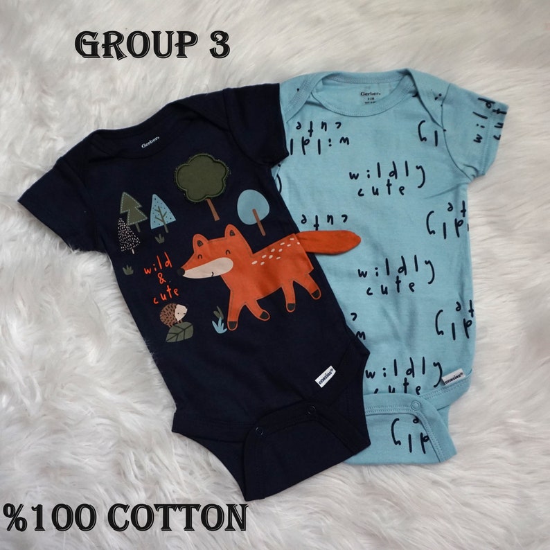 May include: Two baby onesies, one blue with a fox and trees graphic and the text "wild & cute", and one light blue with the text "wildly cute" repeated in a pattern.