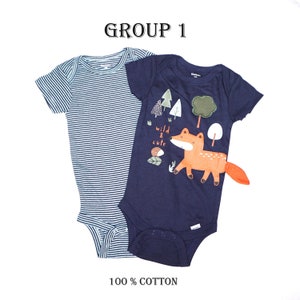 May include: Two baby onesies, one with blue and white stripes and the other with a navy blue background and a fox graphic with the text "wild & cute". The text "GROUP 1" and "100% COTTON" are also visible.