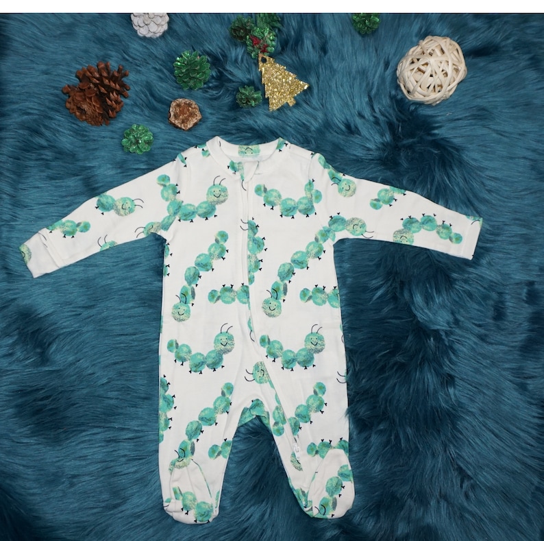 May include: White baby onesie with a green caterpillar print. The onesie has a zipper closure.