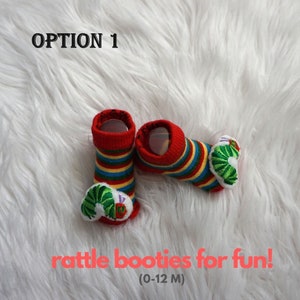 May include: Red and yellow striped baby booties with a green caterpillar design. The booties have a rattle inside. The text "OPTION 1" and "rattle booties for fun! (0-12 M)" is visible in the image.