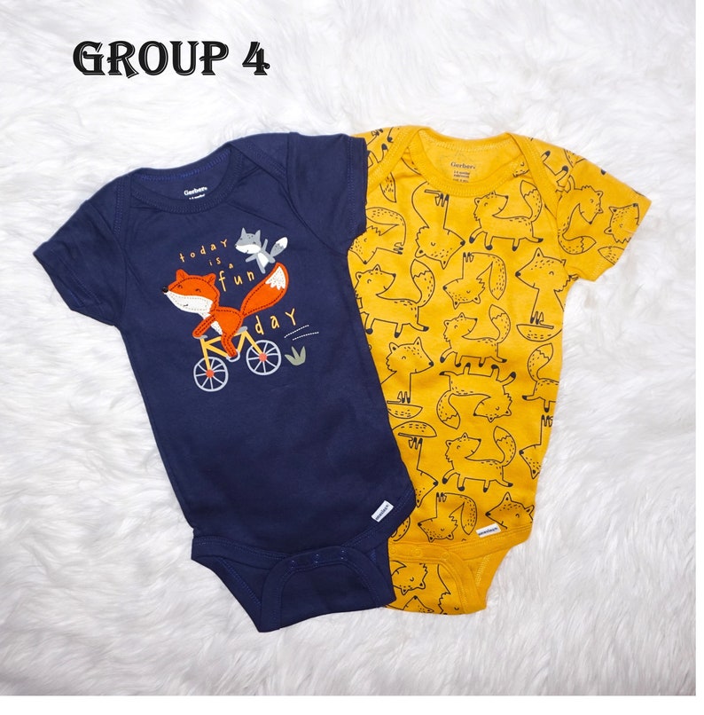 May include: Two baby onesies, one navy blue with a fox riding a bicycle and the text "today is a fun day", and one yellow with a repeating pattern of foxes.