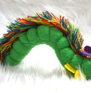 May include: A green plush caterpillar toy with a rainbow-colored mane and a red head with a purple and yellow butterfly wing.
