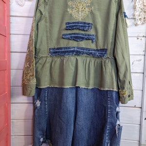 以下が含まれることがあります： 緑色のユーティリティジャケットにデニムスカートが取り付けられています。ジャケットの背中には金色の刺繍が施され、スカートにはダメージ加工が施されています。