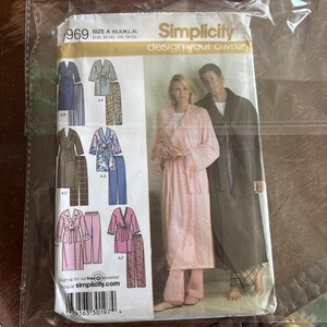 May include: A Simplicity sewing pattern envelope, number 969, featuring illustrations of various robe and pajama sets in sizes XS to XL. The cover displays a photograph of two people wearing a light pink robe and a dark brown robe with matching pants.