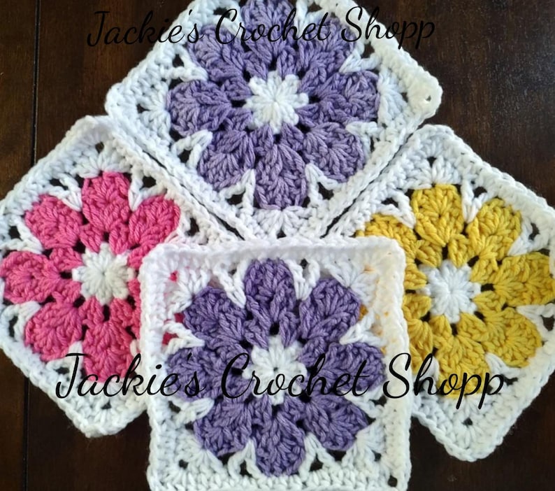 May include: Four crocheted flower squares in pink, purple, yellow, and white. The squares are joined together to form a larger piece. The text "Jackie's Crochet Shopp" is visible in the image.
