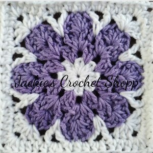 May include: A crocheted square with a purple flower in the center. The flower has five petals and is surrounded by a white border. The text "Jackie's Crochet Shop" is visible in the center of the square.
