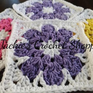 May include: Four crocheted squares with different colored flowers in the center. The squares are white with a white border. The flowers are pink, purple, yellow, and white. The text "Jackie's Crochet Shop" is visible in the center of the image.