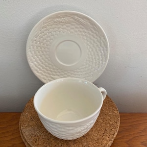 Peut inclure: Une tasse à thé et une soucoupe en céramique blanche avec un motif de panier tissé. La tasse et la soucoupe ont un motif en relief qui ressemble à un panier tissé.