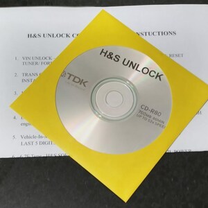May include: A silver CD-R disc labeled "H&S UNLOCK" is nestled in a bright yellow envelope, resting on a white sheet of paper with instructions. The CD is a TDK CD-R80, 700MB, up to 52x speed. The paper has the text "H&S UNLOCK CO INSTRUCTIONS".