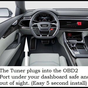 May include: A close-up of the interior of a car with a white leather seat and a black dashboard. An arrow points to the OBD2 port under the dashboard, where a tuner can be plugged in.