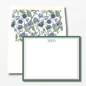 May include: Stationery set featuring a white notecard with a green border and the initials "MPD". The envelope interior displays a floral pattern with blue flowers and green leaves on a white background. The stationery set is perfect for sending personalized notes.