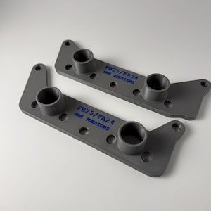 May include: Two identical grey, flat, elongated components featuring two cylindrical protrusions and multiple circular mounting holes. Each piece is stamped with the blue text FB25/PA24 and SNN 3DESIGNS on the top surface.
