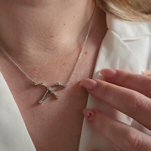 May include: A silver necklace with a constellation pendant featuring small clear stones.