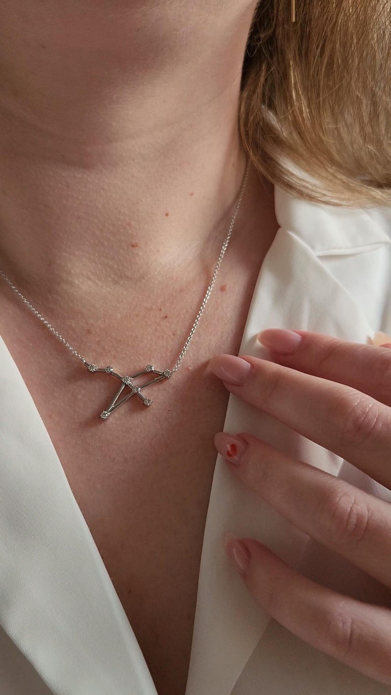 May include: A silver necklace with a constellation pendant featuring small clear stones.