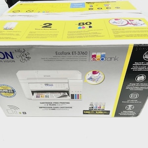May include: Epson EcoTank ET-3760 printer box. The box is white with yellow accents and features the printer's image, along with text indicating cartridge-free printing and wireless capabilities. The box also displays the Epson logo.