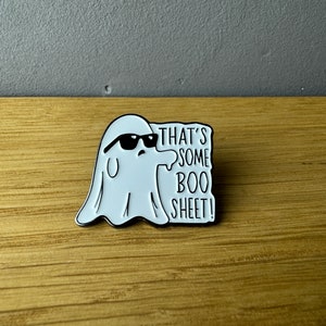 Könnte beinhalten: Weißer Emaille-Pin mit einem Geist, der eine Sonnenbrille trägt und den Text "That's some boo sheet!"