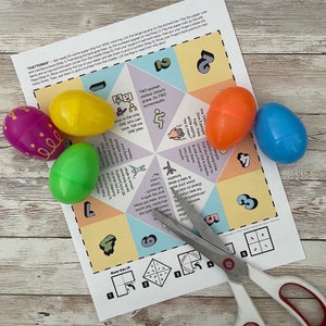 May include: A colourful paper fortune teller with a blank side up and a side with numbers 1-7. The fortune teller is surrounded by six colourful plastic Easter eggs. A pair of scissors is lying on top of the paper.