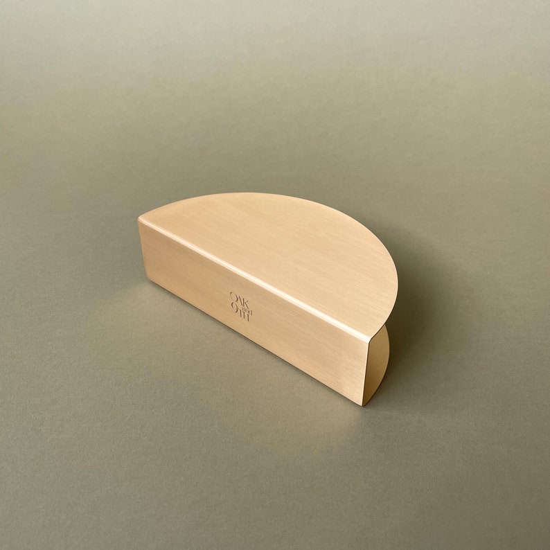 Pu&ograve; includere: Un supporto in metallo color oro a forma di semicircolo con le parole "Oak & Gift" incise sulla superficie.