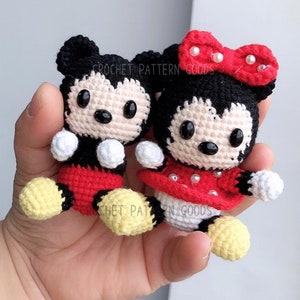 Puede incluir: Un par de muñecas de Mickey Mouse y Minnie Mouse de crochet. Mickey lleva un atuendo rojo y negro con zapatos amarillos. Minnie lleva un vestido rojo con lunares blancos y un lazo rojo con perlas blancas. Ambas muñecas tienen ojos negros y detalles blancos.