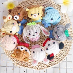 May include: A collection of nine crocheted stuffed animals, including a bear, lion, elephant, bunny, pig, and more. The animals are all wearing different outfits and have cute faces.