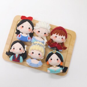 May include: Seven crocheted Disney princess dolls, including Snow White, Elsa, Ariel, Cinderella, Mulan, Jasmine, and Rapunzel. Each doll is handmade and features a unique design and color scheme.