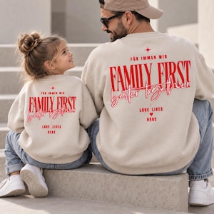 Könnte beinhalten: Zwei beige Sweatshirts mit Rundhalsausschnitt und rotem Text auf der Rückseite. Das Design enthält die Worte "FÜR IMMER WIR", "FAMILY FIRST", "better together" und "LOVE LIVES HERE" mit einem kleinen Stern- und Herzsymbol in fetter Schrift.