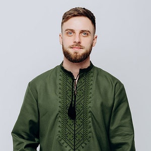 May include: A green long-sleeved shirt with black embroidered details on the front. The shirt has a collar and a button closure.