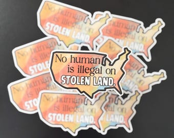 May include: A set of colorful stickers with the text "No human is illegal on stolen land." The stickers are shaped like the United States of America.