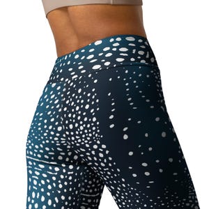 May include: Navy blue leggings featuring a white polka dot design. The leggings have a high waist and a gradient effect, shifting from a dark blue to a lighter tone. The material looks stretchy and form-fitting, suitable for exercise or casual wear.