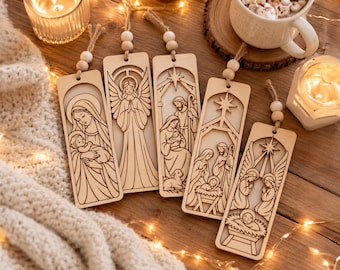 Pode incluir: Cinco marcadores de página retangulares de madeira clara com cenas religiosas cortadas a laser, incluindo a Natividade, um anjo e Maria com o menino Jesus. Cada marcador tem um laço de juta com duas contas de madeira no topo.