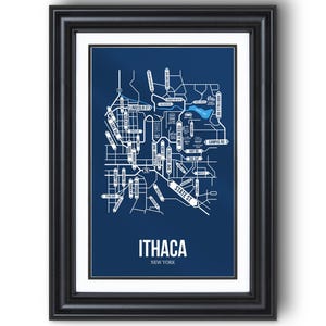 May include: Framed print featuring a detailed white map of Ithaca, New York, set against a deep blue background. The map highlights streets and landmarks, with the city's name prominently displayed in white. The print is encased in a black frame.