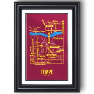 May include: Framed map print of Tempe, Arizona, featuring a maroon background with yellow street names and a blue river. The map is encased in a black frame with a white border, showcasing the city's road network and landmarks.