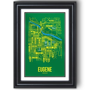 Może przedstawiać: Oprawiony wydruk mapy Eugene, Oregon. Mapa jest żółta na zielonym tle, z nazwami ulic i punktami orientacyjnymi. Słowo "EUGENE" znajduje się na dole, z "OREGON" poniżej. Rama jest czarna.