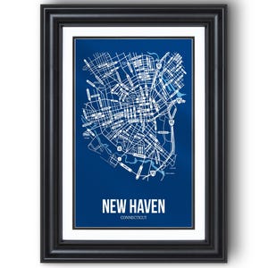 May include: Framed print of a map of New Haven, Connecticut. The map is white on a blue background, with street names and major roads visible. The words "NEW HAVEN CONNECTICUT" are printed in white at the bottom. The frame is black.