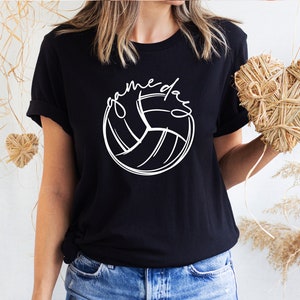 K&ouml;nnte beinhalten: Schwarzes T-Shirt mit einem wei&szlig;en Volleyball-Motiv und dem Text "game day" in einer handschriftlichen Schrift.