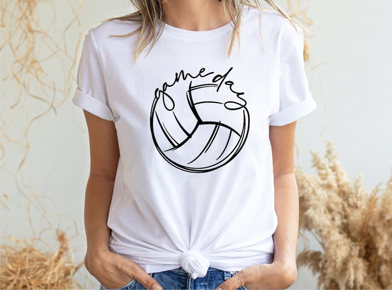 K&ouml;nnte beinhalten: Wei&szlig;es T-Shirt mit einer schwarzen Volleyballgrafik und dem Text "game day" in Schreibschrift.