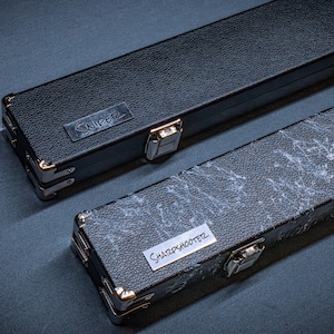 May include: Two rectangular hard cases with metal corner reinforcements and latches. The top case is solid black with a metal plate reading SNIPER. The bottom case features a black and white marbled texture with a label reading SHARPSHOOTER.