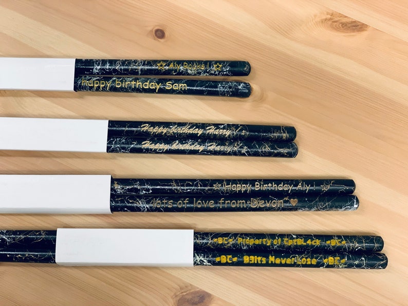 May include: Four pairs of black and gold drumsticks with personalized messages. The messages include "Happy Birthday Sam", "Happy Birthday Harry", "Happy Birthday Aly lots of love from Devon", and "BC B3Its Never Lose".
