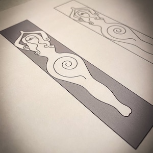 May include: Two rectangular bookmarks with a minimalist design of a female figure. One is on a grey background, the other on a white background. The figure has arms raised, with a spiral on the torso. The artwork is simple and elegant.