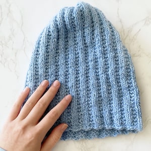May include: A light blue knitted beanie hat with a ribbed texture.
