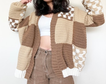 May include: A brown, beige and white crocheted cardigan with a chequered pattern. The cardigan is open at the front and has long sleeves.