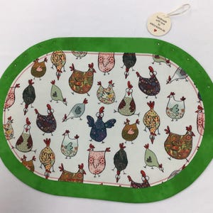 Könnte beinhalten: Grüner ovaler Tischläufer mit weißem Hintergrund und einem Muster aus bunten Hühnern. Der Text "handmade with love by eddecor.de" ist auf einem weißen Etikett gedruckt.