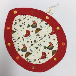 Könnte beinhalten: Roter ovaler Platzdeckchen mit einer weißen Mitte, die ein sich wiederholendes Muster aus Hühnern und Küken zeigt. Der Platzdeckchen hat einen roten Rand mit gestickten Blumen.
