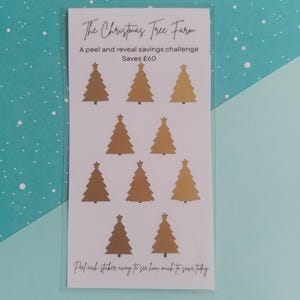 Könnte beinhalten: Eine transparente Plastikkarte mit dem Text "The Christmas Tree Farm" und "A peel and reveal savings challenge Saves £60". Neun goldene Weihnachtsbaum-Aufkleber sind abgebildet.