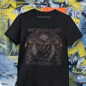 May include: Black t-shirt featuring a brown and white graphic print of a band called "Meshuggah" with the album title "Koloss" printed below the graphic.
