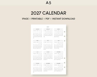 Op de afbeelding: Een witte A5-kalenderpagina voor 2027 met twaalf maanden in een raster. De tekst luidt 2027 CALENDAR, 1PAGE, PRINTABLE, PDF, INSTANT DOWNLOAD. De lay-out bevat kolommen voor de dagen van de week en genummerde data voor elke maand.